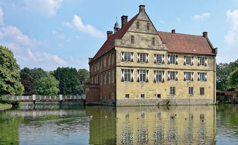 Droste Pad - Burg Hülshoff mit der Sandsteinfassaden spiegelt sich an einem hellen Sommertag in der Kräfte